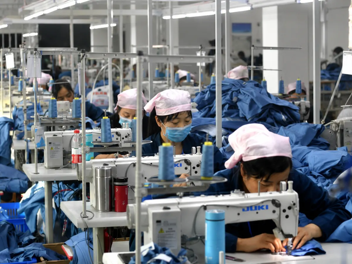 Garment workers sewing blue apparel on a Guangzhou factory production line